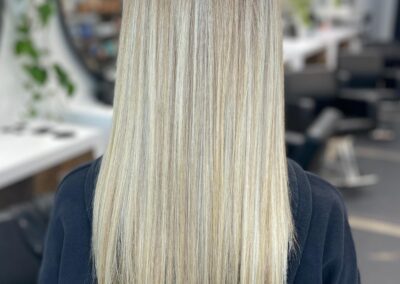 A woman with long blonde hair in front of a mirror.