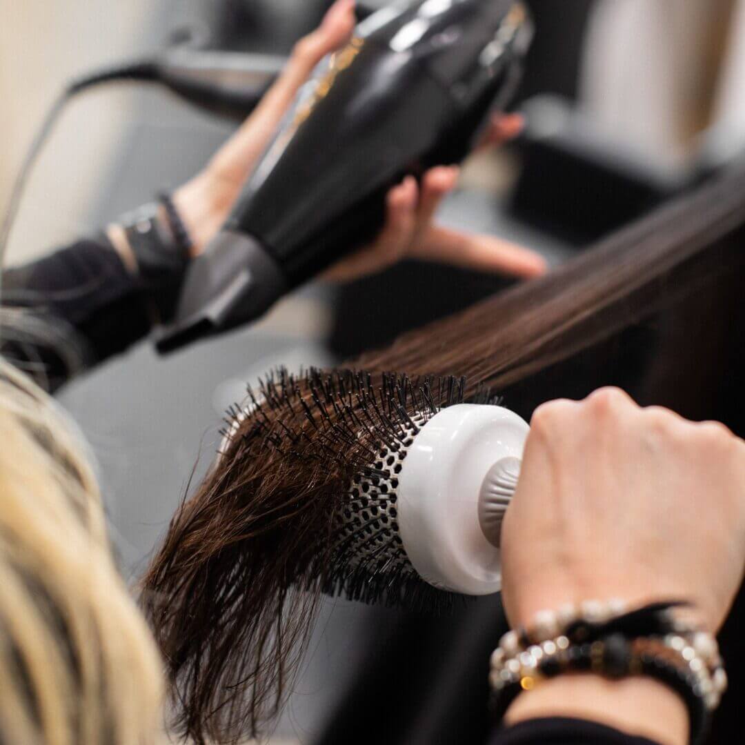 A person blow drying their hair in the salon.