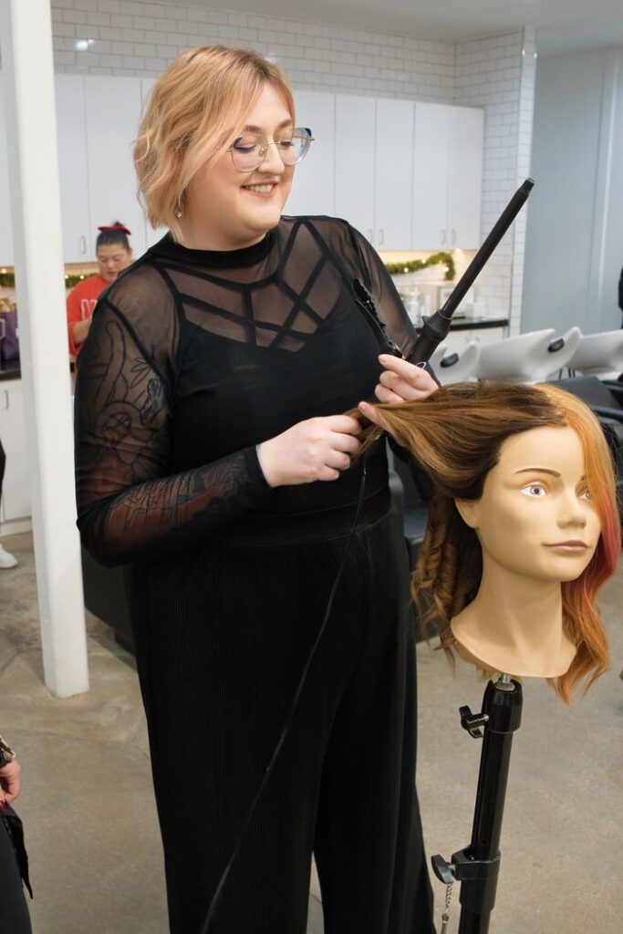 Stylist curling hair in salon.